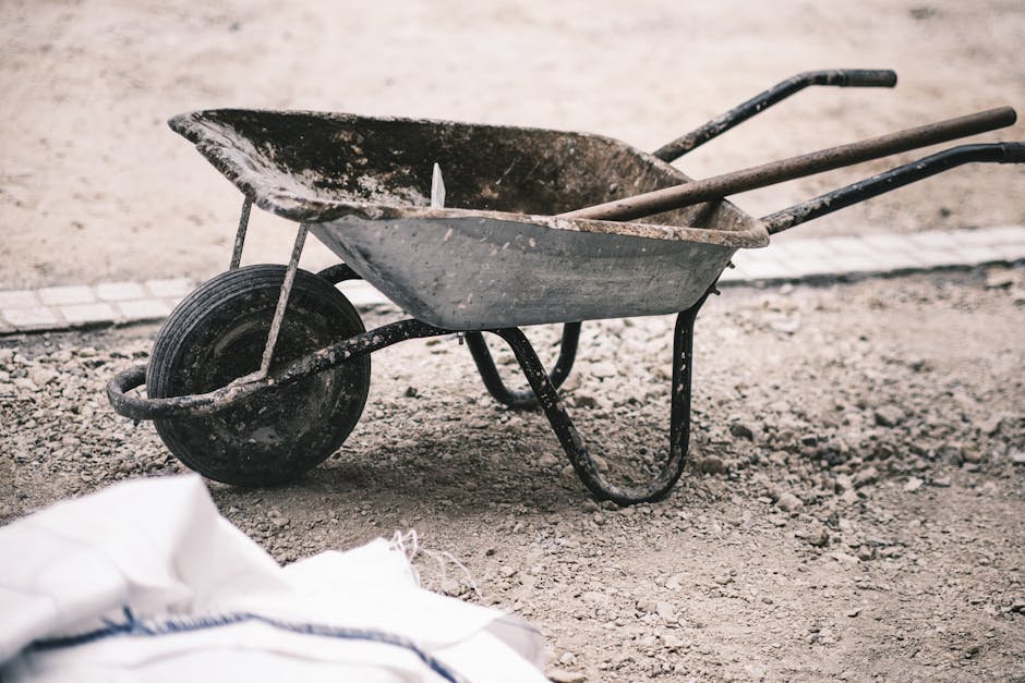 An old wheelbarrow on a gravel construction site, highlighting rustic work tools.
